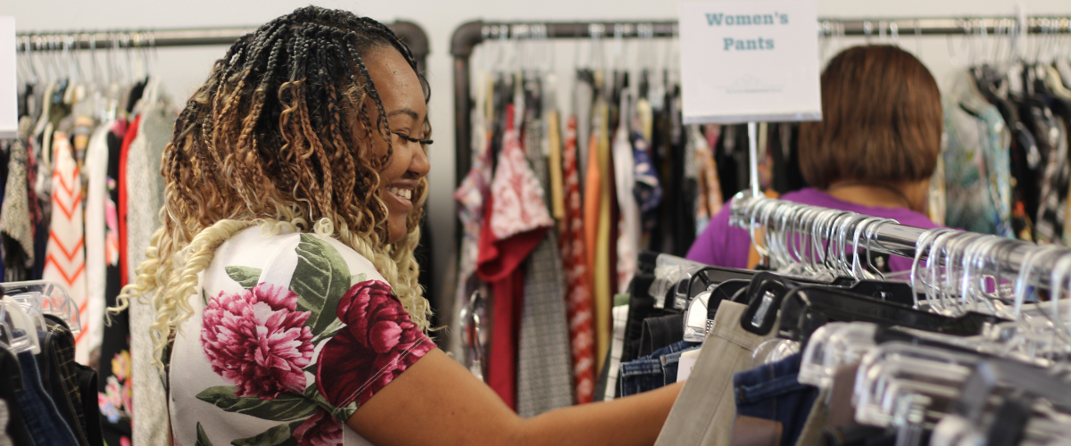 Woman smiling looking at clothes at thrift store