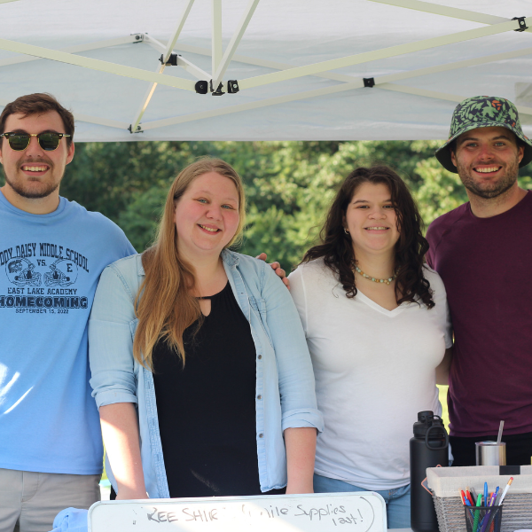 Group of people standing behind informational booth, smiling.