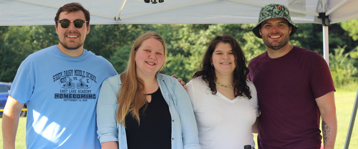 Group of people standing behind informational booth, smiling.