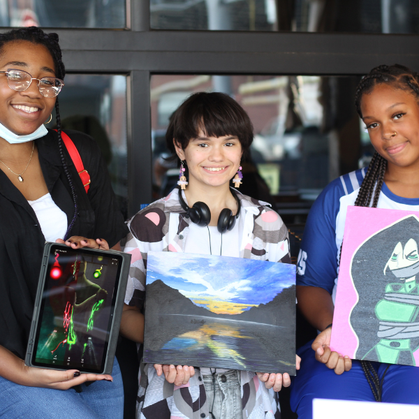 High School students holding up their own original artwork.